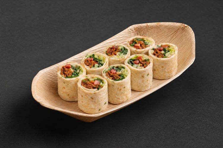 Acht Wrap-Häppchen mit Bulgur und Paprika in einer länglichen Servierschale
