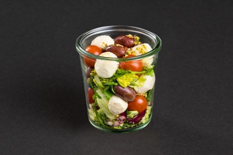 Caprese Salat mit Tomaten, Mozzarella und Pesto im Glas angerichtet für Catering im Büro