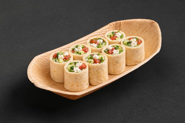 Acht Wrap-Häppchen mit Feta und Gemüse in einer Servierschale